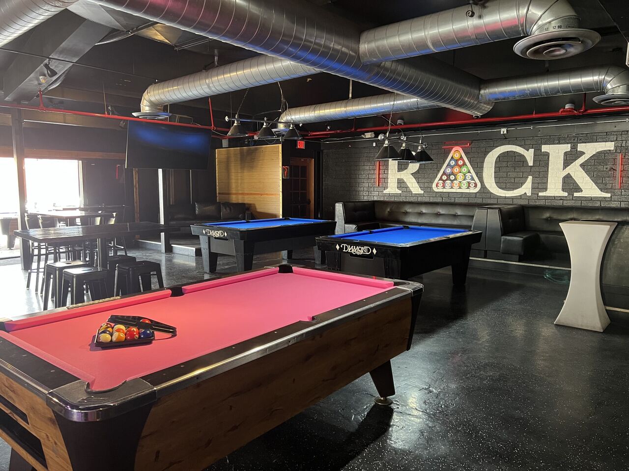 The pool room at Rack in Old Town Scottsdale, with pink and blue felt tables and the RACK wall graphic